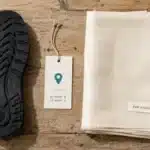 EU deforestation regulation compliance: a pair of rubber-soled boots and a roll of viscose fabric on a supplier inspection table, with a geolocation pin icon overlay