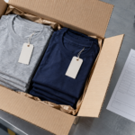 De minimis tariff impact on apparel: a customs-declared parcel of folded cotton T-shirts on a fulfillment table